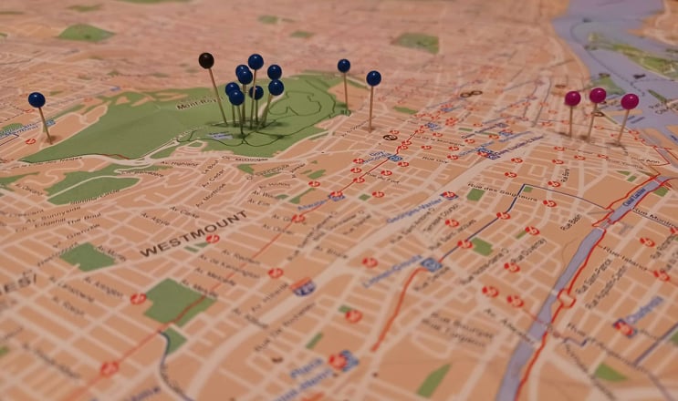 Photographie d’une carte de la ville de Montréal et de plusieurs punaises bleu marine et d’une, noire.